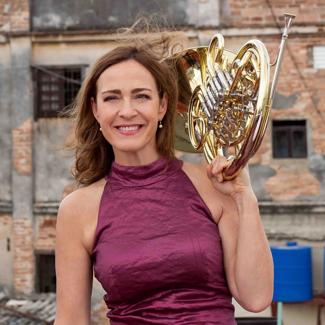 Sarah Willis con vestido y Trompa en la mano