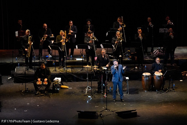 Rubén Blades vestido de azul en el escenario con su orquesta